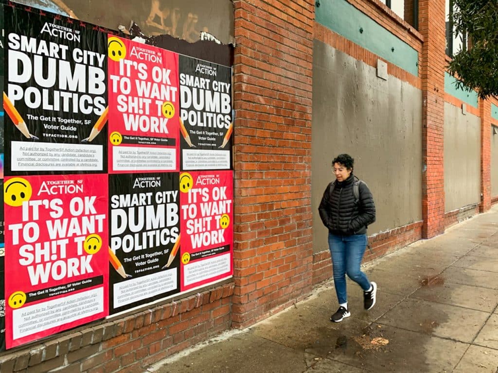 Urban wall with fly posters promoting bold political and social messages in a high-traffic area.